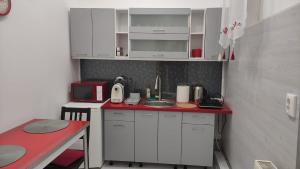 a small kitchen with white cabinets and a red counter top at Cluj Center in Cluj-Napoca
