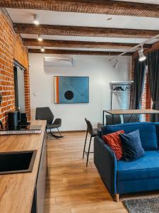 a living room with a blue couch and a brick wall at 1880 Apartment with Private Parking in Marijampolė