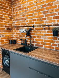 a kitchen with a sink and a brick wall at 1880 Apartment with Private Parking in Marijampolė