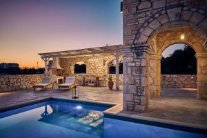 una piscina al aire libre en un edificio de piedra con patio en Ioanna Château - Luxury Stone Villa, en Maryiés