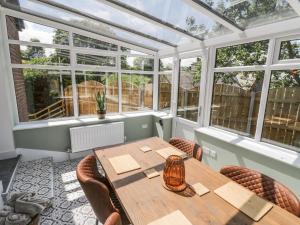 een serre met een tafel, stoelen en ramen bij Foulsyke Farm Bungalow in Saltburn-by-the-Sea