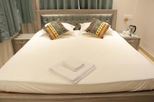 ein weißes Bett mit herzförmiger Serviette darauf in der Unterkunft LA CRESTA INN in Kalkutta