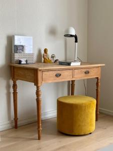 a wooden table with a lamp and a yellow stool at Havgassens in Sæby