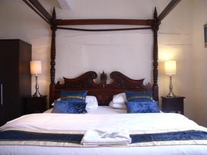 a bedroom with a large bed with blue pillows at THE SARACENS HEAD INN in Amersham