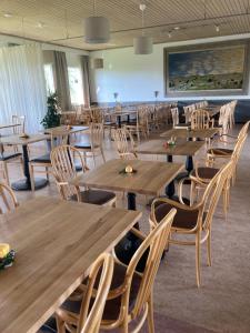 uma sala de jantar com mesas e cadeiras de madeira em Allégården Kastlösa Hotell em Kastlösa