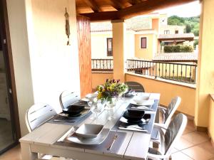 a dining table with white chairs and a balcony at Oasi delle Onde in Villasimius
