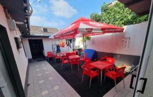 um pátio com mesas e cadeiras vermelhas e um guarda-sol em AmA em Constança
