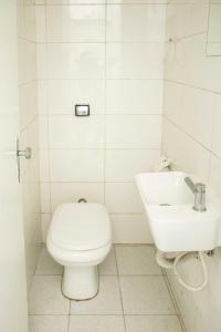 a white bathroom with a toilet and a sink at Casa Ecotrips Barra Funda - Hostel in São Paulo