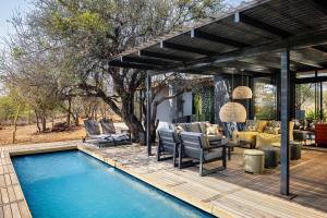um pátio com uma piscina, cadeiras e uma mesa em Garangani 360 - Self-Catering Villa em Golders Green