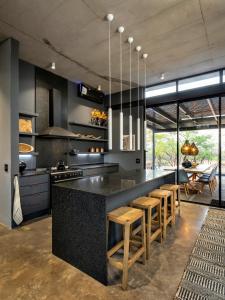 a kitchen with a black counter and wooden stools at Garangani 360 - Self-Catering Villa in Golders Green