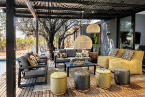 um pátio com sofás, uma mesa e bancos em Garangani 360 - Self-Catering Villa em Golders Green