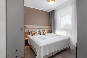 een slaapkamer met een bed met witte lakens en een raam bij Miedzyzdroje SEASIDE Apartments Bel Mare by Renters in Międzyzdroje