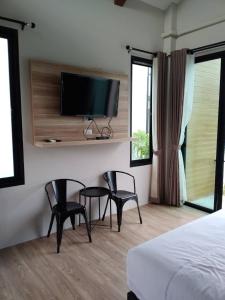 a bedroom with two chairs and a television on a wall at Pailin Place in Chanthaburi