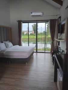 - une chambre avec un lit et une porte coulissante en verre dans l'établissement Pailin Place, à Chanthaburi