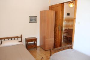 a bedroom with two beds and a wooden cabinet at Circe Pansion in Lixouri