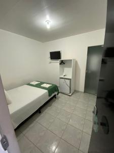 1 dormitorio pequeño con 1 cama y TV en Pousada Vela Mar, en Maragogi