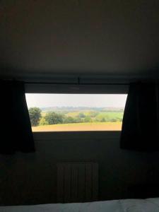 ein Fenster in einem Schlafzimmer mit Blick auf ein Feld in der Unterkunft Le logis du Chesnot in Saint-Quentin-sur-le-Homme