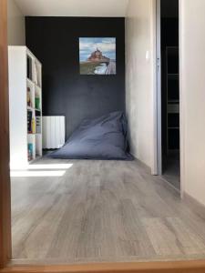 1 dormitorio con cama azul y espejo en Le logis du Chesnot en Saint-Quentin-sur-le-Homme