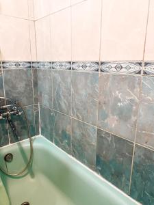 La salle de bains carrelée est pourvue d'une baignoire verte. dans l'établissement apartment near metro station Darnitsa, à Kiev