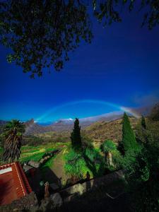 einen Regenbogen am Himmel über einem Feld mit Palmen in der Unterkunft Mountain Hostel Finca La Isa in Tejeda