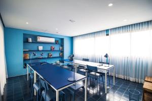 una habitación con mesas y sillas y una pared azul en Vossa Bossa Bela Vista, en São Paulo