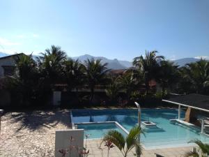 une piscine avec des palmiers et des montagnes en arrière-plan dans l'établissement Pousada do Veleiro Azul, à Angra dos Reis