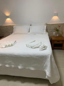 Una cama blanca con dos toallas blancas. en Pousada Chale Cana Brava en Guaramiranga