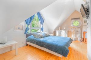 sypialnia z łóżkiem z niebieską kołdrą i oknem w obiekcie Cottages à proximité de la plage w mieście Dinard