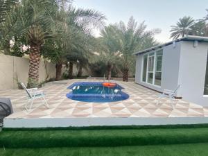 uma piscina com duas cadeiras e uma casa em Dar Alhamra INN نزل دار الحمراء em Al Hamra