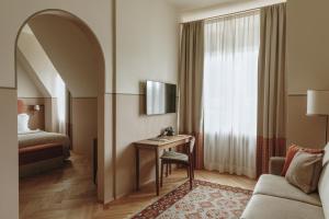 a hotel room with a desk and a bed at Parkhotel Mondschein, a Member of Design Hotels in Bolzano