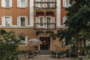 a building with tables and chairs and an umbrella at Parkhotel Mondschein, a Member of Design Hotels in Bolzano