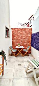 un patio con 2 sillas, una mesa y una pared de ladrillo en Casa da Avó Isaura - Ericeira, en Ericeira