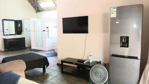 a living room with a refrigerator and a tv at Thatch Haven Guesthouse in Centurion