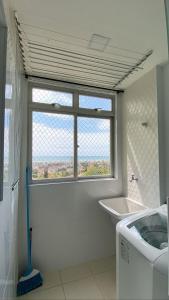 a white bathroom with a window and a sink at Atlântico condomínio in Serra +37 photos