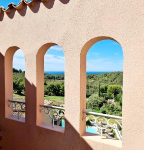 a view from the balcony of a building with two arches at HAMEAU DES AMANDIERS - vue mer, golf et vignes in Saint-Cyr-sur-Mer