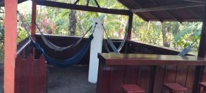 a porch with a hammock and a table and chairs at Gecko de Tortuguero in Tortuguero