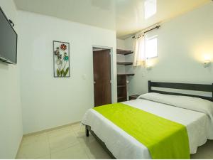 um quarto com uma cama com um cobertor verde em ApartaHotel Luxury em Paipa