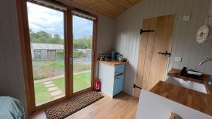 a small kitchen with a large window in a house at Shepherds Hut at Cedar Gables in Lamberhurst