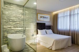 um quarto com uma cama e uma banheira num quarto em Victory Business Hotel em Juiz de Fora