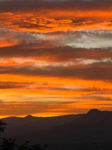 einen Sonnenuntergang am Himmel mit Bergen im Hintergrund in der Unterkunft Casa Rural Lucía es una casa rural amplia con patio ideal para familias in Cabezas Bajas