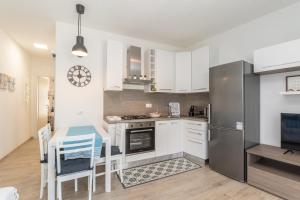 kuchnia z białymi szafkami, stołem i lodówką w obiekcie Stella Marina beach house w mieście Isola Rossa +19 zdjęć