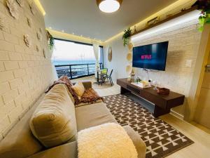 uma sala de estar com um sofá e uma televisão de ecrã plano em Flat Luxuoso Alto Padrao Frente Mar com 2 suites no Iate Plaza em Fortaleza