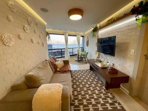 uma sala de estar com um sofá e uma televisão em Flat Luxuoso Alto Padrao Frente Mar com 2 suites no Iate Plaza em Fortaleza