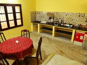 a dining room with a red table and chairs and a kitchen at Smith Guest House in Puducherry