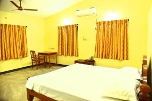 a bedroom with a bed and a table and windows at Smith Guest House in Puducherry
