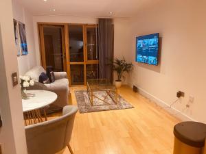 a living room with a table and a tv on the wall at Deluxe City Apt, River Canal View& Free Parking! in Leeds