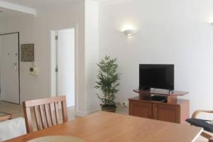 une salle à manger avec une table et une télévision sur un support dans l'établissement Cosy flat, Salgados Village, à Guia