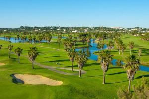 une vue sur un terrain de golf avec des palmiers dans l'établissement Cosy flat, Salgados Village, à Guia