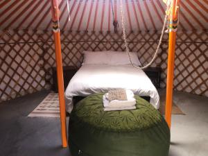 a bed in a yurt with a green ottoman at 28 Palms Ranch in Twentynine Palms