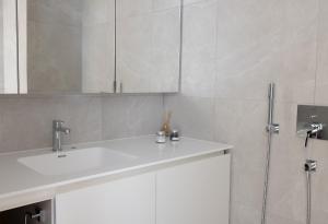 W białej łazience znajduje się umywalka i lustro. w obiekcie 2ndhomes Beautiful & Modern Attic Studio in Kruununhaka w Helsinkach